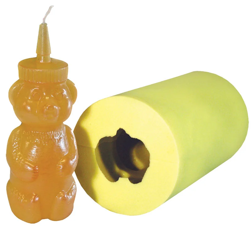 Amber bear-shaped candle beside the yellow silicone mold used to cast it