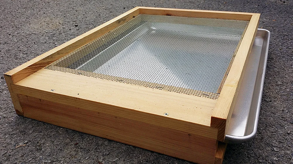 Wooden screened bottom board with a metal tray beneath the wire mesh